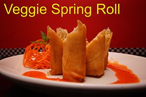 Veggie Spring Rolls cut standing pretty on plate surrounded by sweet sauce